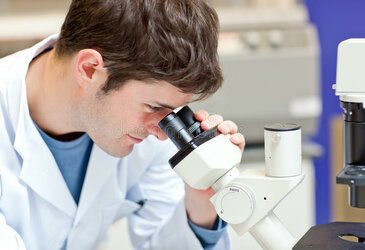 male-scientist-looking-microscope-16262123.jpg
