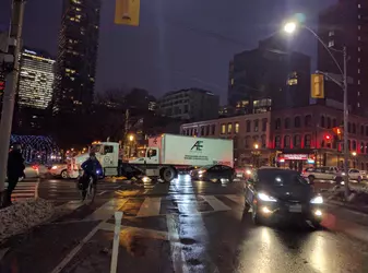 White semi tractor trailer blocking a city intersection, with gridlocked traffic and a cyclist trying to make his way through.