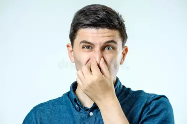 man-holding-his-nose-against-bad-smell-over-gray-background-97737844.webp