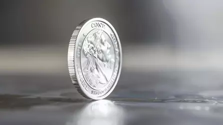 silver-coin-is-placed-reflective-surface-coin-is-tilted-side-so-that-viewer-can-see-details-d...webp